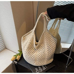 Close-up of beige hollow-out woven tote bag with tulips and books in French style setting