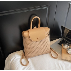Detail of hollow-woven straw backpack with brown faux leather flap and gold hardware