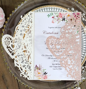 Detail view of laser cut wedding invitation with glitter paper and intricate floral patterns