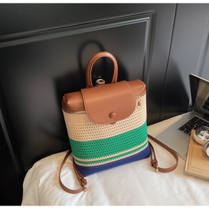 Detail of color-block woven backpack with leather flap in a cozy lifestyle setting