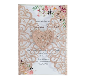 Detail of laser-cut glitter gold wedding invitation with floral card and heart pattern