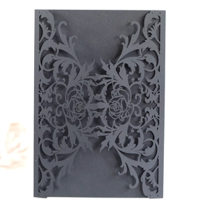 Detail of laser-cut black engagement invitation card with intricate rose vine patterns