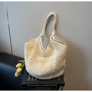 Detail of beige hollow woven straw tote bag with grid texture on a black book