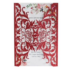 Close-up of laser-cut red glitter wedding invitation with floral patterns and insert