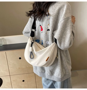 Detail of white nylon hobo bag with adjustable strap and side orange label