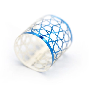 Detail of laser-cut metal napkin ring featuring star patterns and blue gradient finish