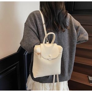 Detail showing the cream woven texture and leather flap of the stylish mini backpack
