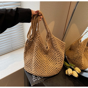 Detailed macro view of the hollow handwoven straw tote bag texture in natural khaki color