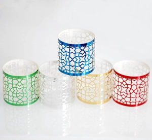 Macro view of five metallic napkin rings with geometric hollow patterns in various colors