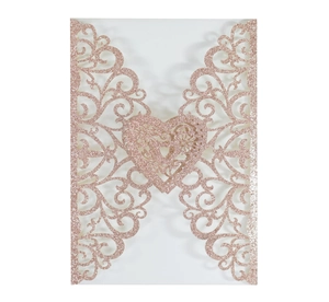 Macro detail of laser-cut rose gold glitter wedding invitation with heart pattern