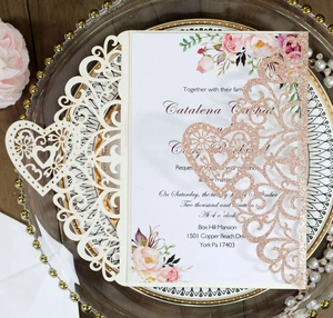 Detail of laser-cut wedding invitation with rose gold glitter and floral inner card