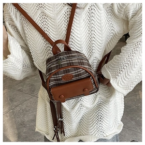 Close-up of vintage plaid mini backpack with brown leather flap pocket and logo detail