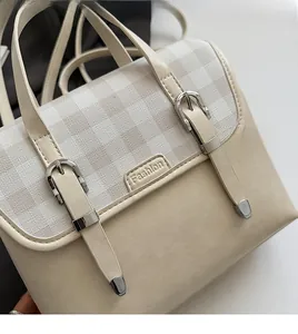Detail of beige vintage backpack showing plaid fabric texture and silver metal buckles