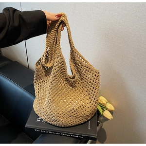 Detail of hand-woven straw tote bag with mesh hollow pattern on a black leather background