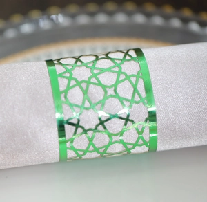Close-up of green metallic napkin ring with geometric cutout on white satin cloth