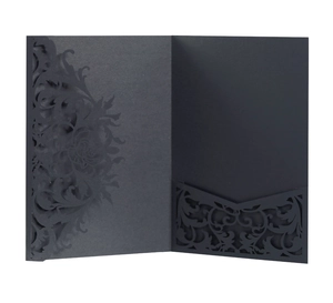 Macro view of laser-cut floral vine patterns on black pearlescent paper invitation