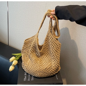 Detail showing hand-held khaki woven mesh tote bag with minimalist indoor aesthetic decor