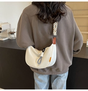 Model wearing white crescent bag with ethnic geometric strap in a cafe setting