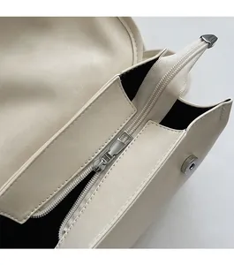 Detailed macro shot of the cream PU leather backpack with a secure zipper and magnetic buckle