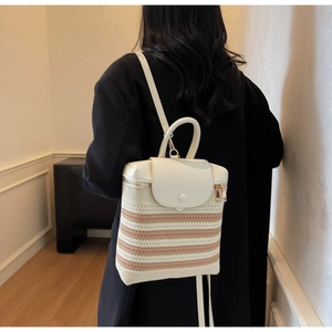 Detail of striped straw backpack with white leather trim and gold metal hardware