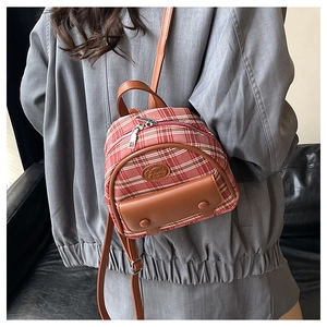 Detail of red and white plaid mini backpack with brown leather flap and embossed logo