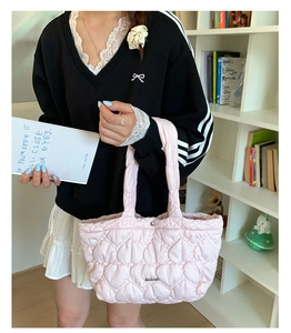 Detailed heart quilting texture on a light pink nylon tote bag held by a model