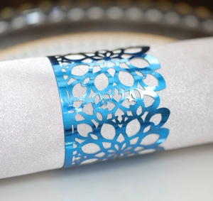 Macro detail of laser-cut blue napkin ring with geometric hollow pattern on a white napkin