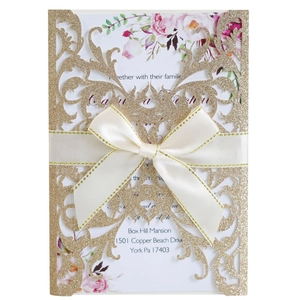 Laser cut glitter wedding invitation with floral insert and satin bow on white background