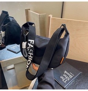Detail of black crescent crossbody bag with white FASHION letter strap and rope knot decor