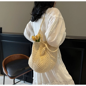 Detail of hand-woven crochet mesh tote bag in cream white with floral dress