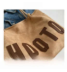 Detail of suede tote bag featuring brown leather HAOTU letter embroidery and neat stitching