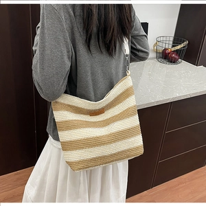 Detail der gestreiften Stricktasche mit Leder-Logo und gewebtem Schultergurt