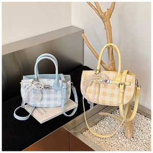 Detail of plaid handbags featuring elegant pearl strands and lace bow decorations