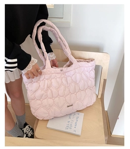 Close-up of pink quilted tote bag showing detailed heart embroidery and soft texture