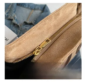 Detailed macro view of smooth gold metal zipper on khaki suede tote bag with clean stitching