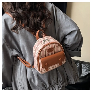 Detailed shot of mini pink plaid backpack featuring a brown leather flap pocket and straps