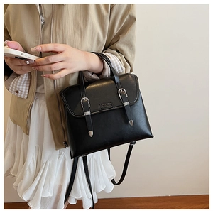 Detail of black vintage PU leather backpack featuring silver buckles and fashion plaque