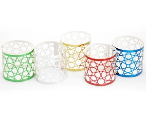 Detail of five multicolor geometric hollow napkin rings in gold, red, blue, green and silver