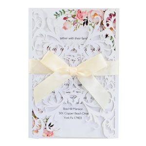 Elegant laser-cut floral wedding invitation with cream silk bow and floral insert