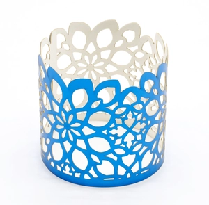 Macro view of blue cut-out metal napkin ring with floral hollow patterns and white lining