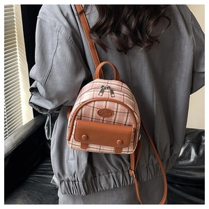 Detail view of pink plaid mini backpack featuring vintage brown leather straps and accents