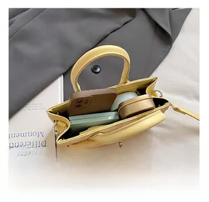 Spacious interior of yellow leather plaid handbag with smartphone and cosmetic items