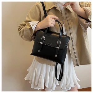 Classic black vintage satchel with silver buckles and handle shown on a casual model