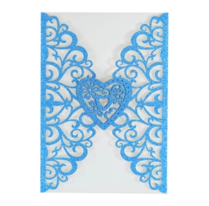 Close-up of laser-cut wedding invitation in blue glitter paper with floral scroll patterns