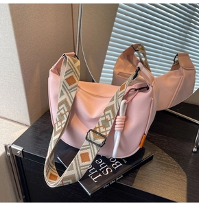 Detail of pink canvas crossbody bag with geometric woven strap and cotton tassel ornament