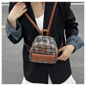 Outdoor model shot of a mini vintage checkered backpack with brown leather trim detailing