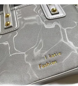 Close-up of light gray bucket bag with water ripple texture and golden rivets details