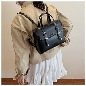 Side view of model wearing black vintage PU leather backpack with metallic buckle detail