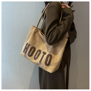 Detail of suede tote bag featuring brown HOOTO letter patches and vintage texture