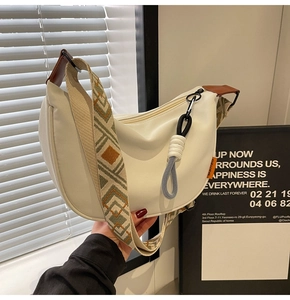 Detail of white canvas hobo bag with ethnic geometric strap and brown leather accents